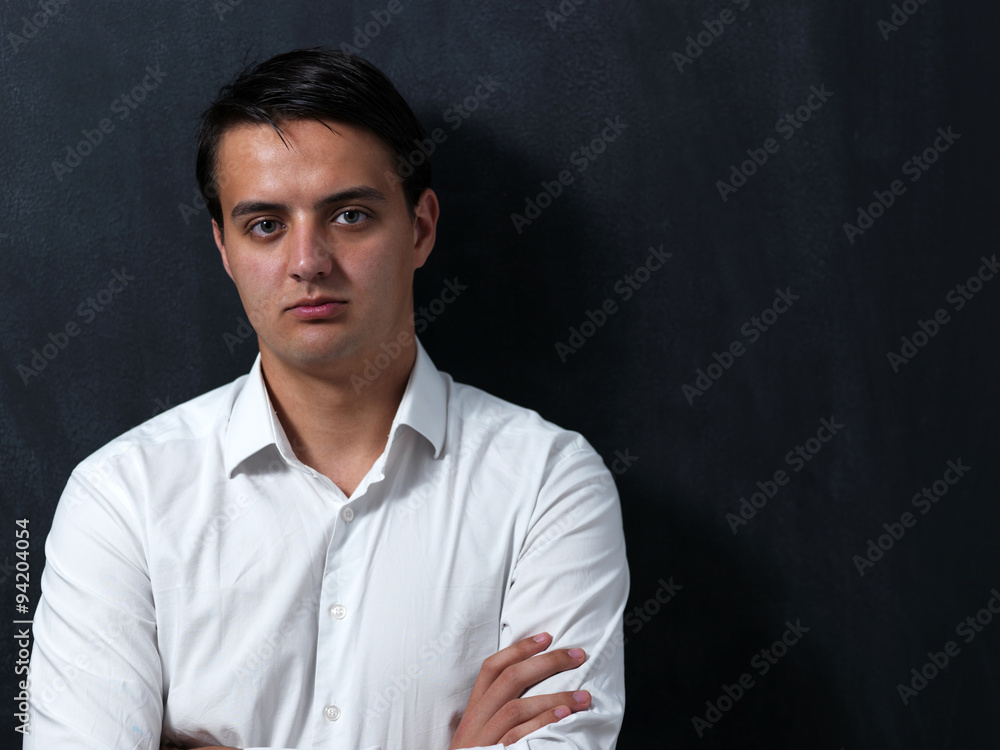 Portrait of a serious young man standing against chalkboard