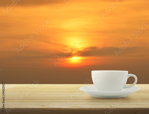 White cup on wooden table over sky