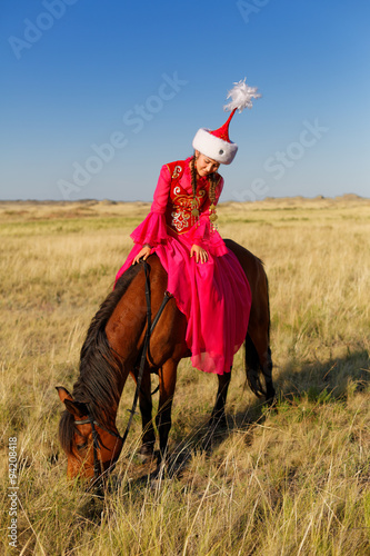 Красивая казашка в национальном костюме в степи на коне photo