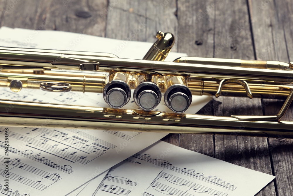 Obraz premium Trumpet and sheet music on old wooden table. Vintage style.