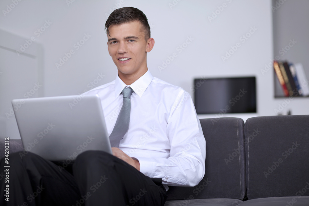 Happy young businessman looking and smiling us, sitting on couch Happy young businessman looking and smiling us, sitting on couch