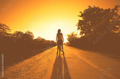 silhouette of woman at sunset with bicycle and happy