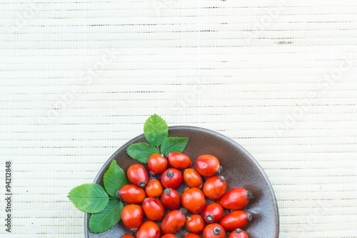 Red wild briers out of bowl on the wooden table photo