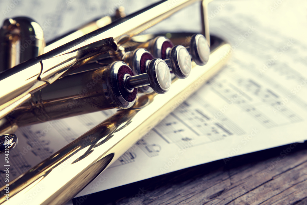 Obraz premium Trumpet and sheet music on old wooden table. Vintage style.