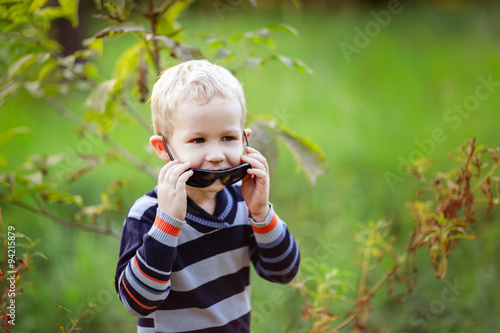 autumn baby boy playing with sunglasses forest