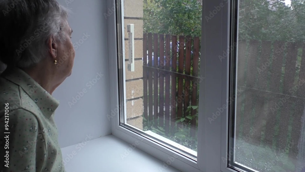 An elderly woman looks out the window An elderly woman looks out the window