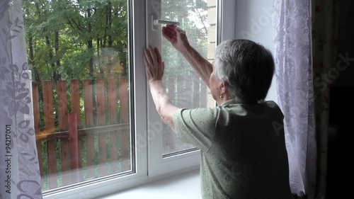 An elderly woman changes position window opening