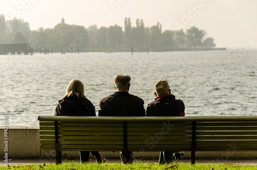 Tableau sur toile Rentner sitzen auf Bank mit Blick auf See