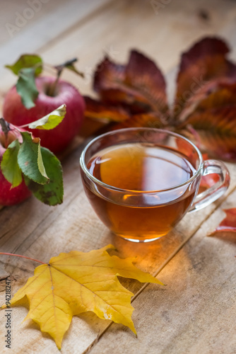 glass hot cup of tea on a wooden table with autumn leaves and ap