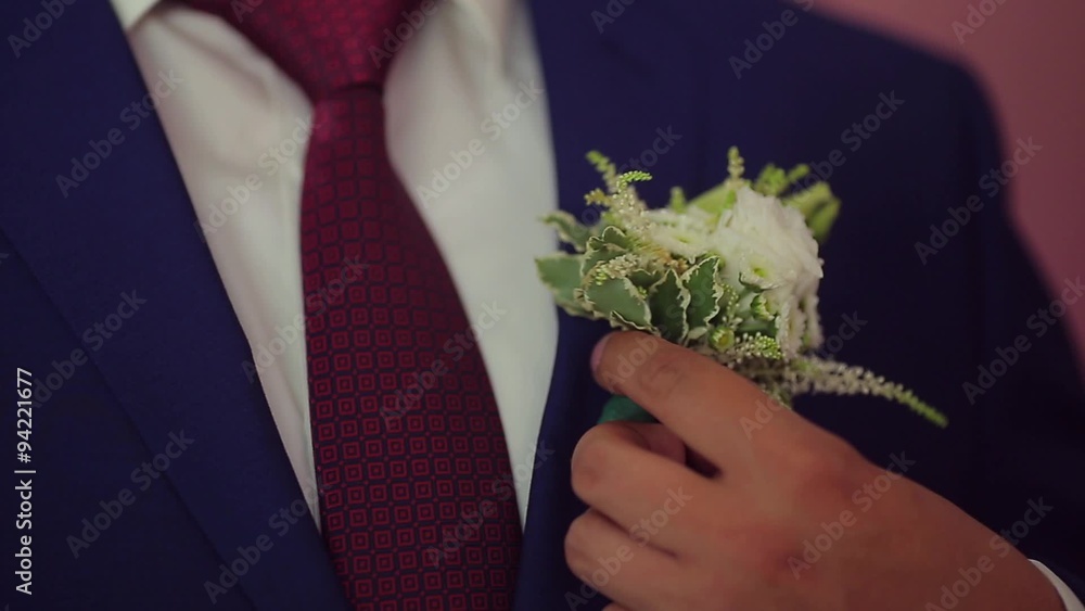 the groom corrects a buttonhole
