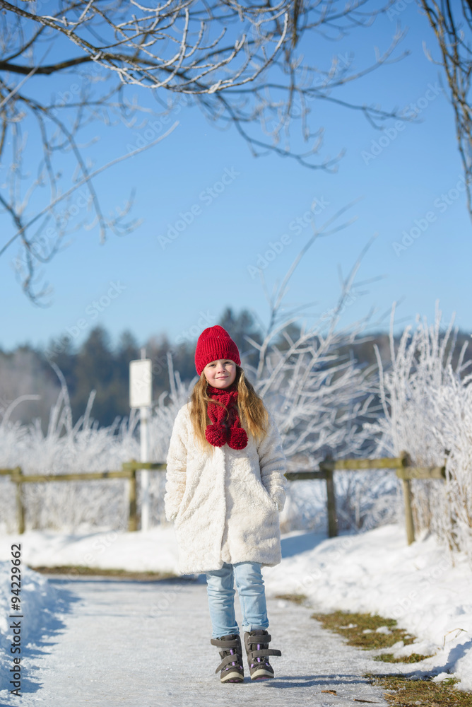 Smiling girl walking in winter forest on a sunny day