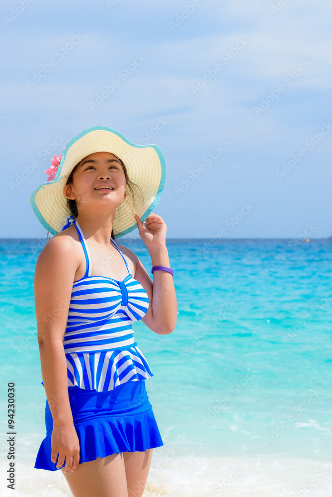 Tourist girl in a blue white swimsuit stand and looking up with happy on the beautiful beach and sea during summer at Koh Miang Island, Mu Ko Similan National Park, Phang Nga province, Thailand