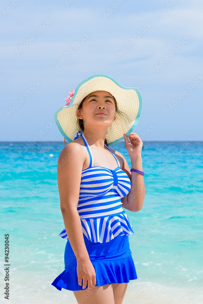 Tourist girl in a blue white swimsuit stand and looking up with happy on the beautiful beach and sea during summer at Koh Miang Island, Mu Ko Similan National Park, Phang Nga province, Thailand