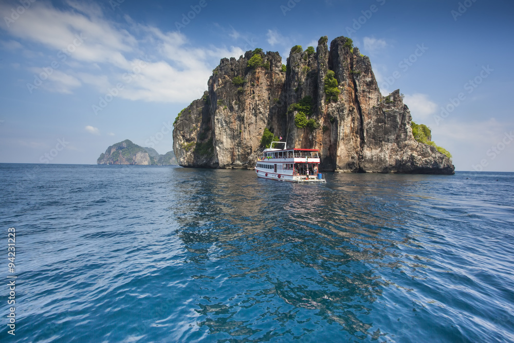 Tourist boat over a big beautiful rock in a bay