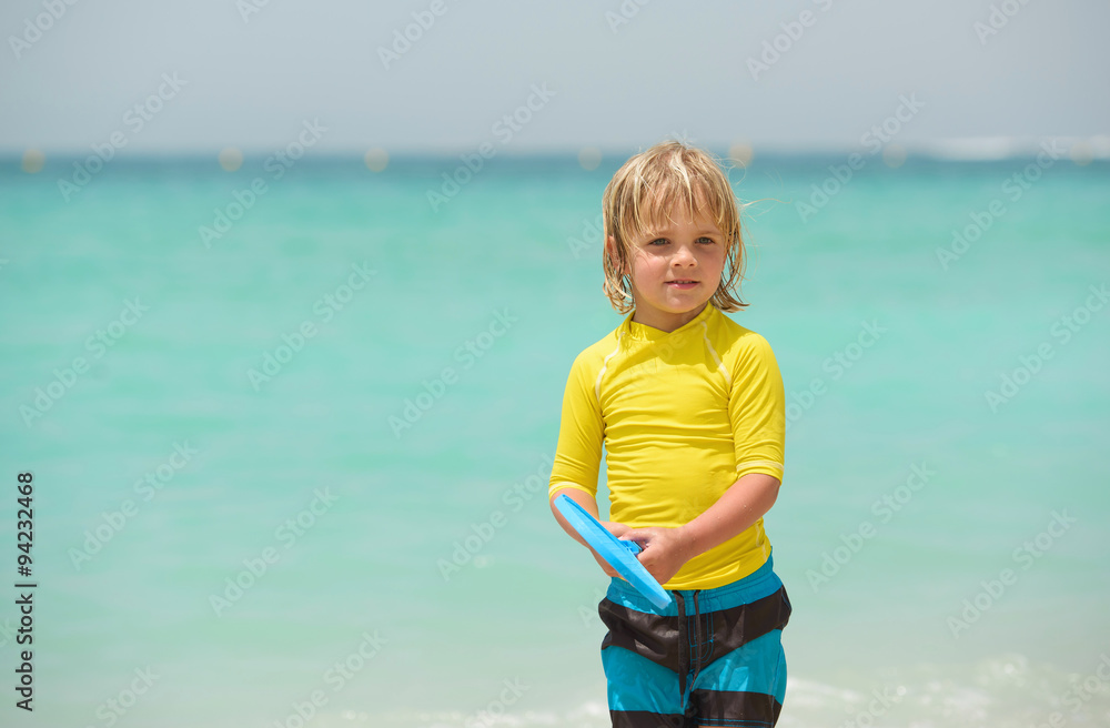 Little boy plays beach tennis on summer vacation