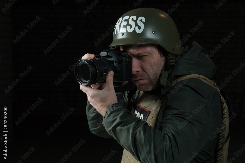 Photojournalist in a helmet and flak jacket wore protective equipment for shooting in hot spot Photojournalist in a helmet and flak jacket wore protective equipment for shooting in hot spot
