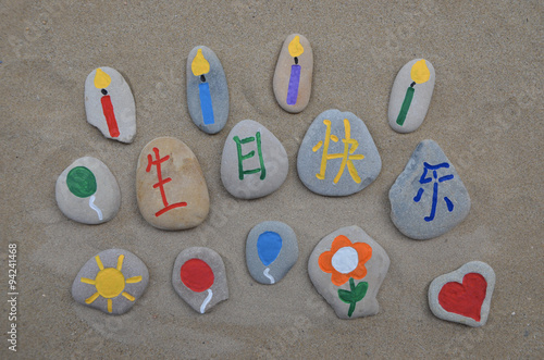 Happy Birthday in chinese mandarin with carved and colored stones over beach sand