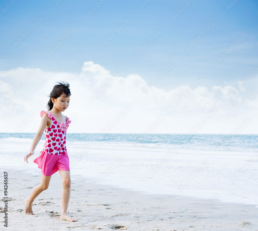 Young Asian girl in pink swim suit walk on the white sand beach Young Asian girl in pink swim suit walk on the white sand beach