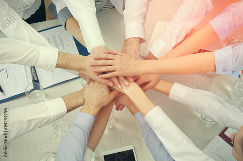 United hands of business team on workspace background top view