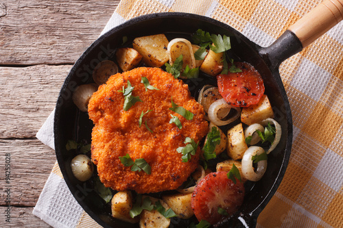 Weiner schnitzel with vegetables in a pan closeup. Horizontal top view 