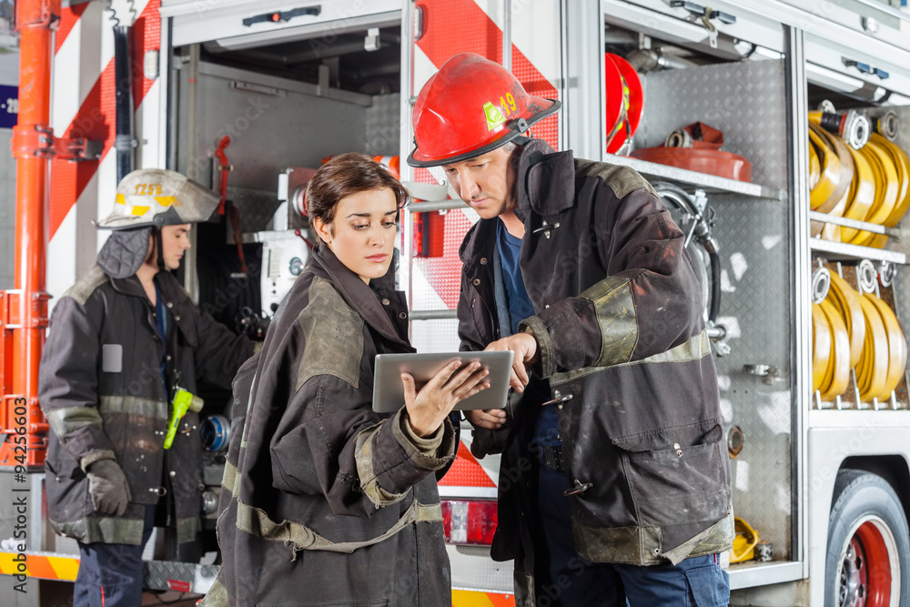 Fototapeta premium Firefighters Using Tablet Computer Against Truck