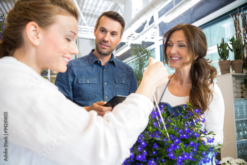 Florist Assisting Couple In Buying Purple Flower Plant
