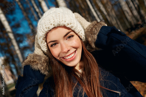 Portrait of a beautiful very cute autumn girl a knitted cap in city park. Fall woman portrait of happy lovely and beautiful caucasian young woman in forest in fall colors.