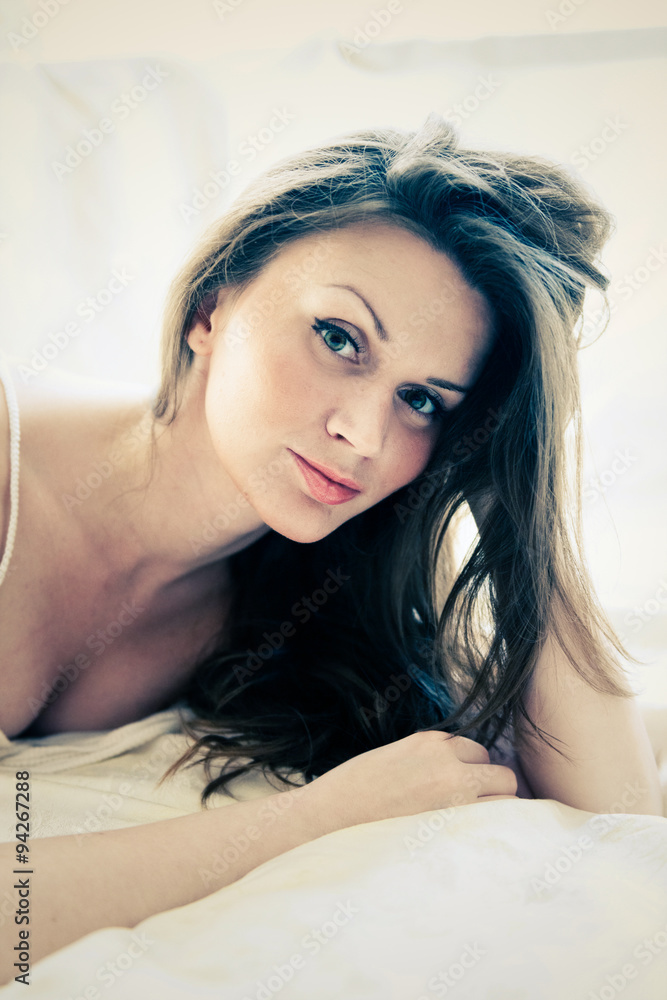 brown-haired woman lying on her duvet in her bedroom brown-haired woman lying on her duvet in her bedroom