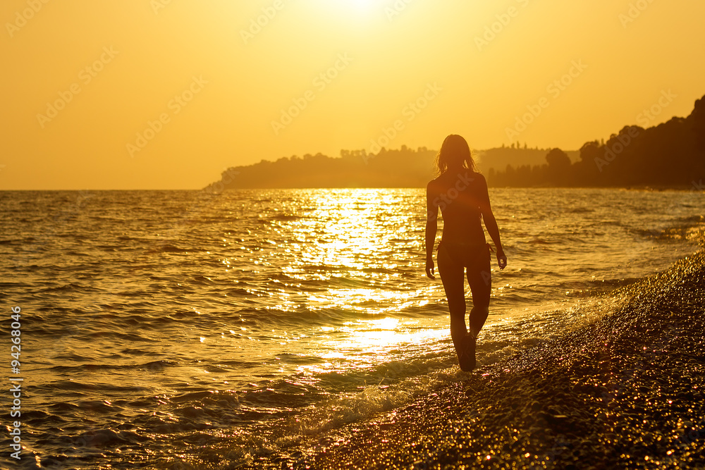 The girl goes on a beach at sunset