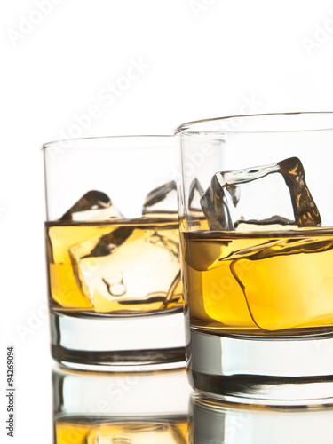 Two glasses of whiskey on the rocks over white background