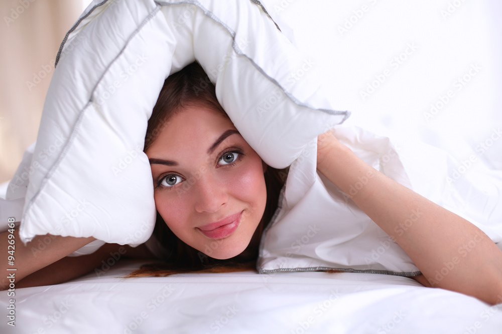 Female lying on bed and closing her ears with pillow Female lying on bed and closing her ears with pillow