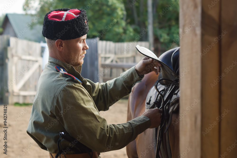 Fototapeta premium Cossack grooming horse in the stall