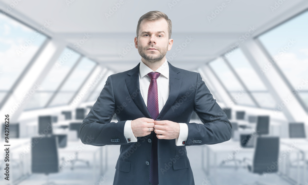 A handsome professional is buttoning up the suit. Bright modern panoramic roof loft office. The concept of luxury consulting services. A handsome professional is buttoning up the suit. Bright modern panoramic roof loft office. The concept of luxury consulting services.