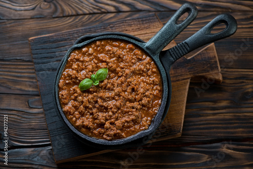 Frying pan with bolognese sauce on a rustic wooden background