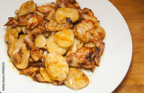Octopus with paprika and potatoes on a white plate, also known a