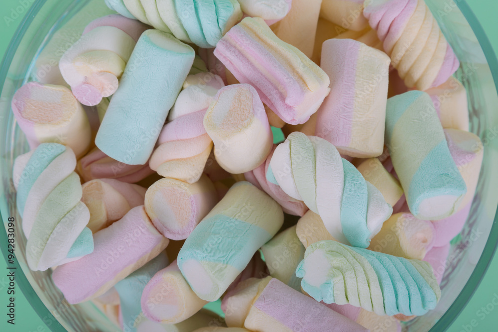 marshmallow candies of different colors in the glass on the background of turquoise. top view. entertainment for children in celebration. marshmallow candies of different colors in the glass on the background of turquoise. top view. entertainment for children in celebration.