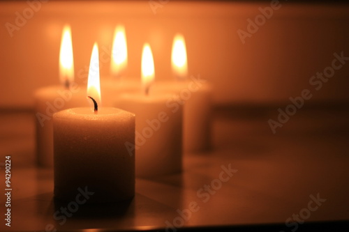 Holiday candles burning on a white background and reflected.