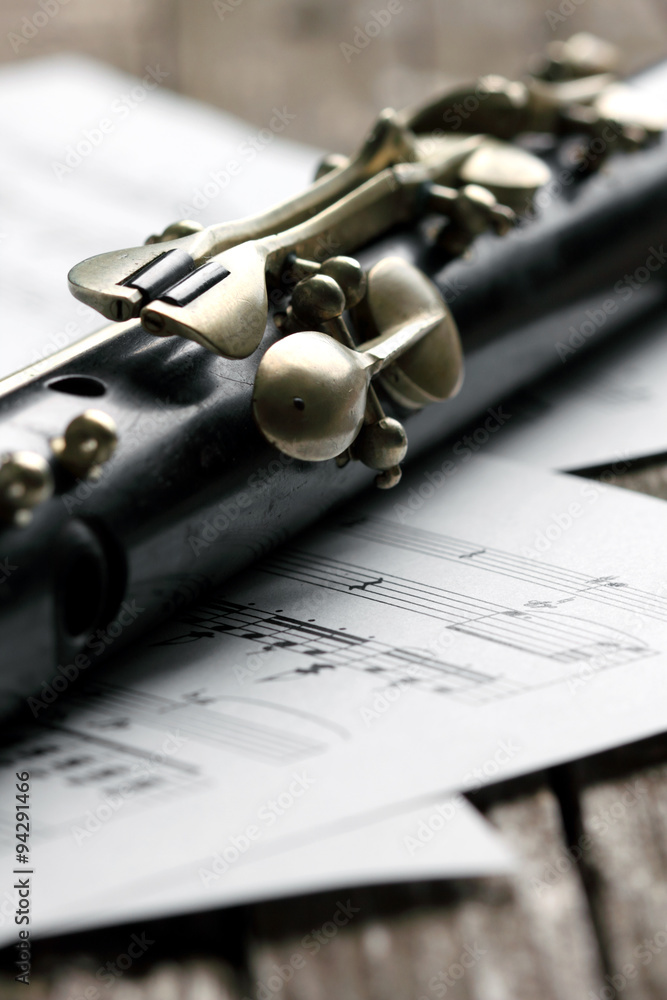 Fototapeta premium Old black flute and music notes on rusty wooden table