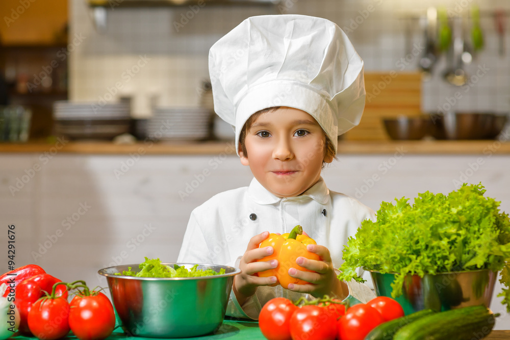 Little smiling Chef boy preparing healthy food at kitchen. the
