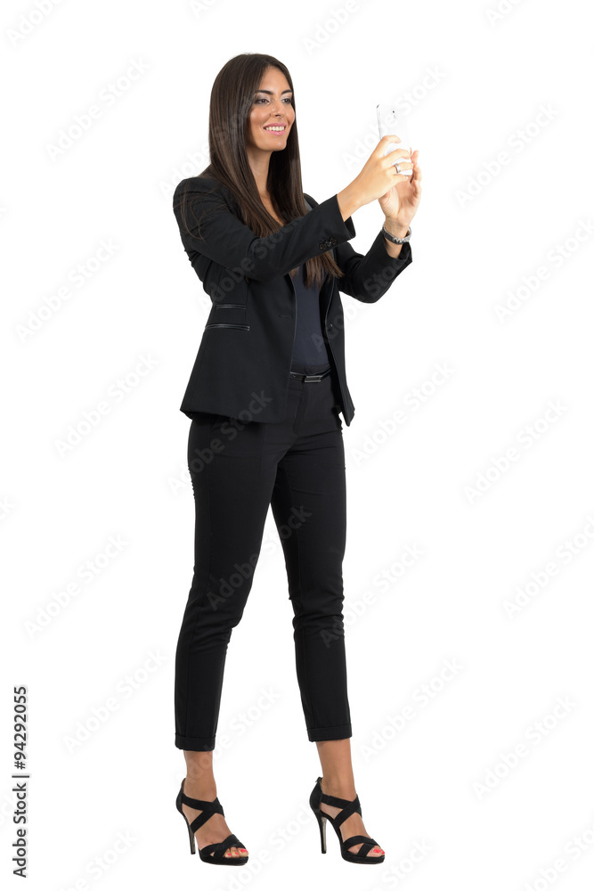 Smiling corporate woman in formal black suit taking photo with cellphone isolated Smiling corporate woman in formal black suit taking photo with cellphone isolated