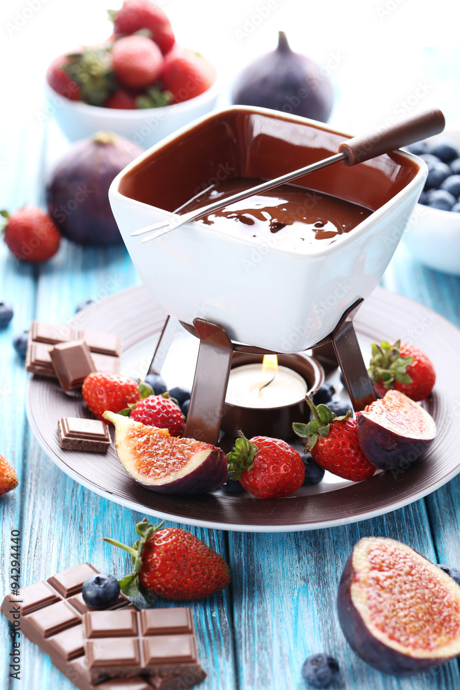 Chocolate fondue with fresh berries on a blue wooden table Chocolate fondue with fresh berries on a blue wooden table