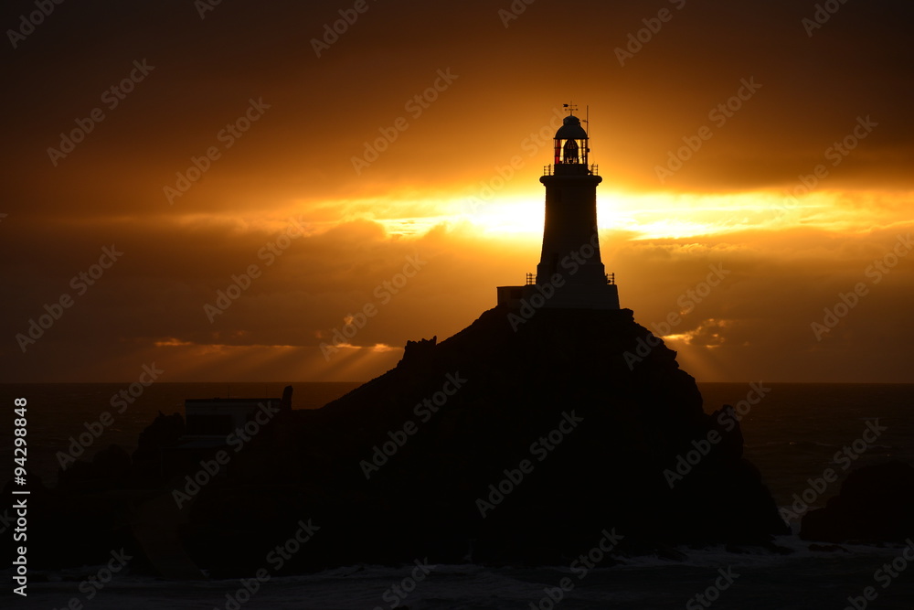 La Corbiere lighthouse, Jersey, U.K.  Telephoto image of a coastal structure backlit by an Autumn sunset.