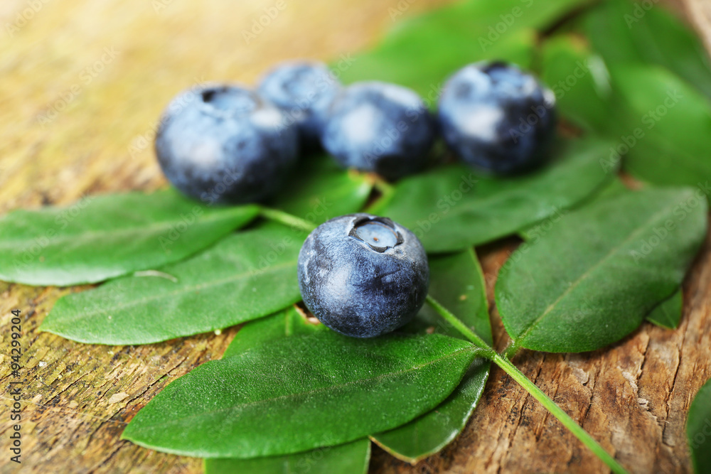 Fresh blueberries with green leaves on wooden table, closeup Fresh blueberries with green leaves on wooden table, closeup