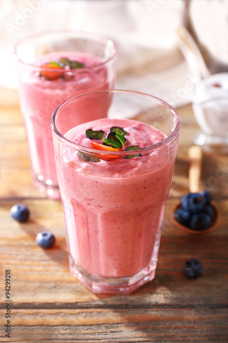 Glasses of berry smoothie on wooden table, closeup