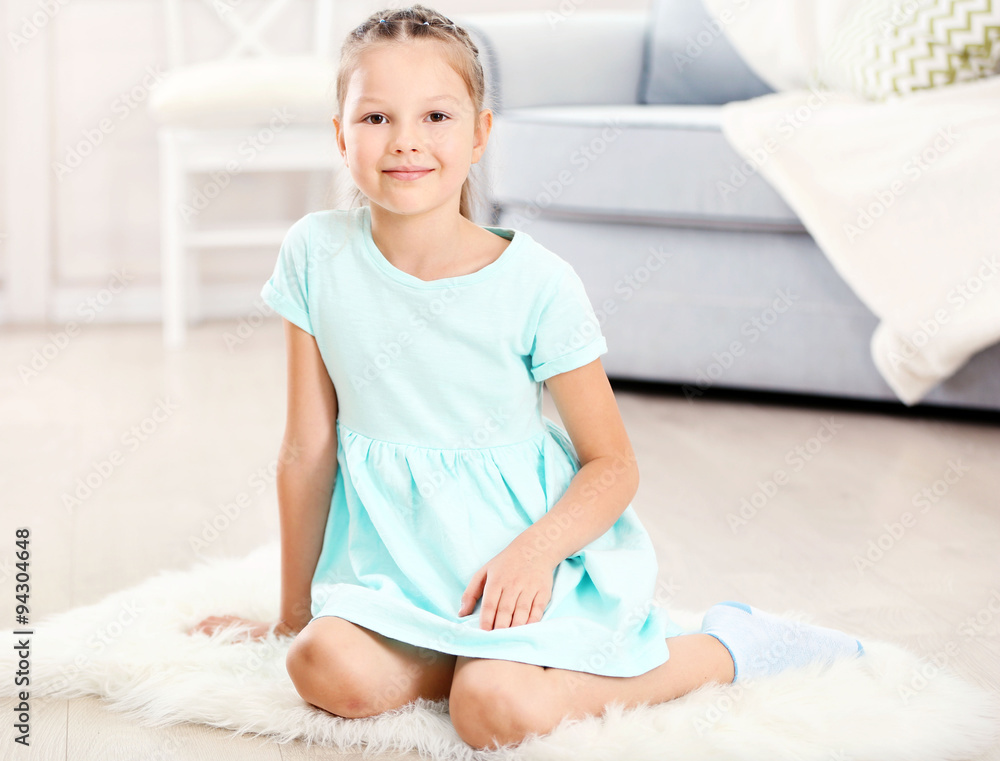 Little cute girl sitting on carpet, on home interior background Little cute girl sitting on carpet, on home interior background