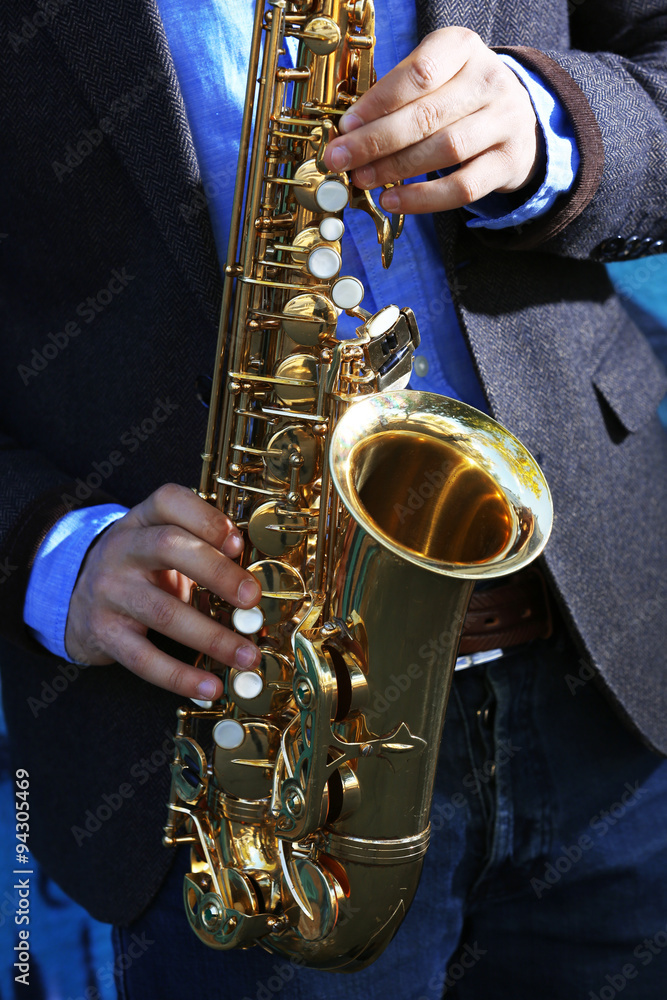 Fototapeta premium Saxophonist plays jazz on the street, close up
