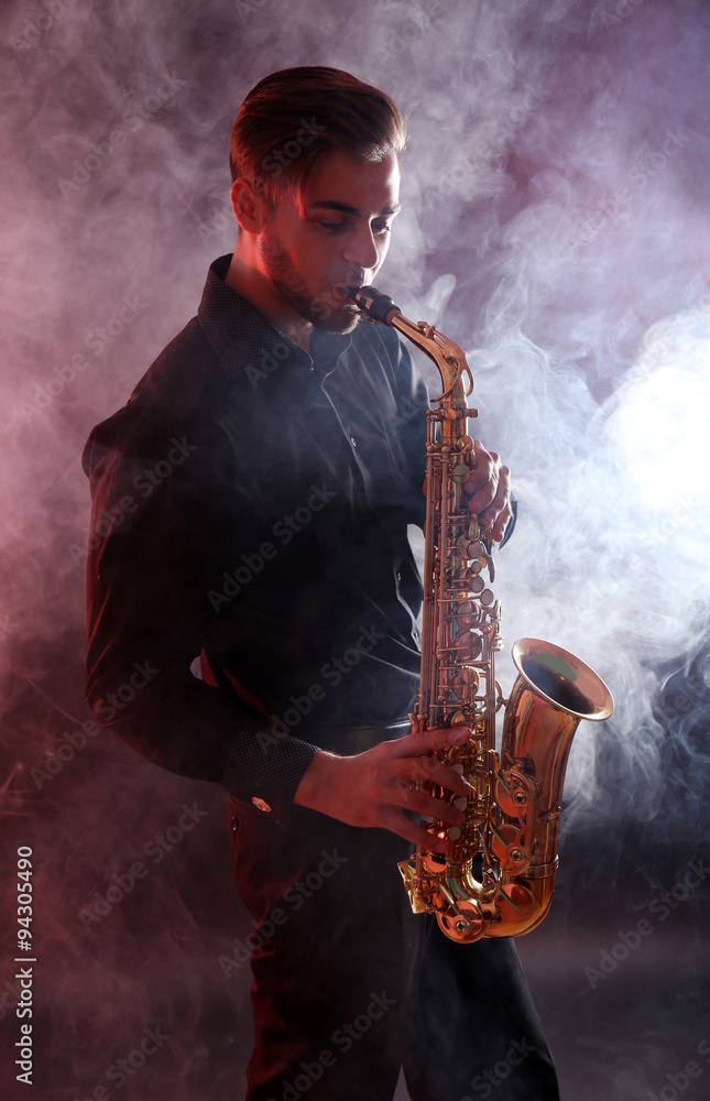 Obraz premium Young man professionally plays sax in red smoke