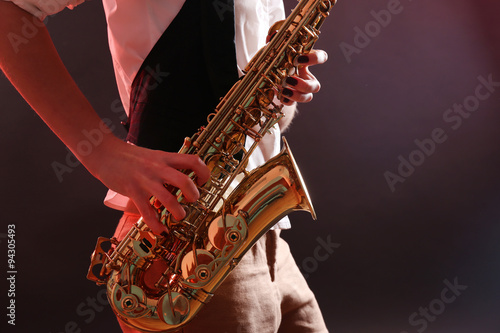 Photography Saxophone in female hands on dark background, close up