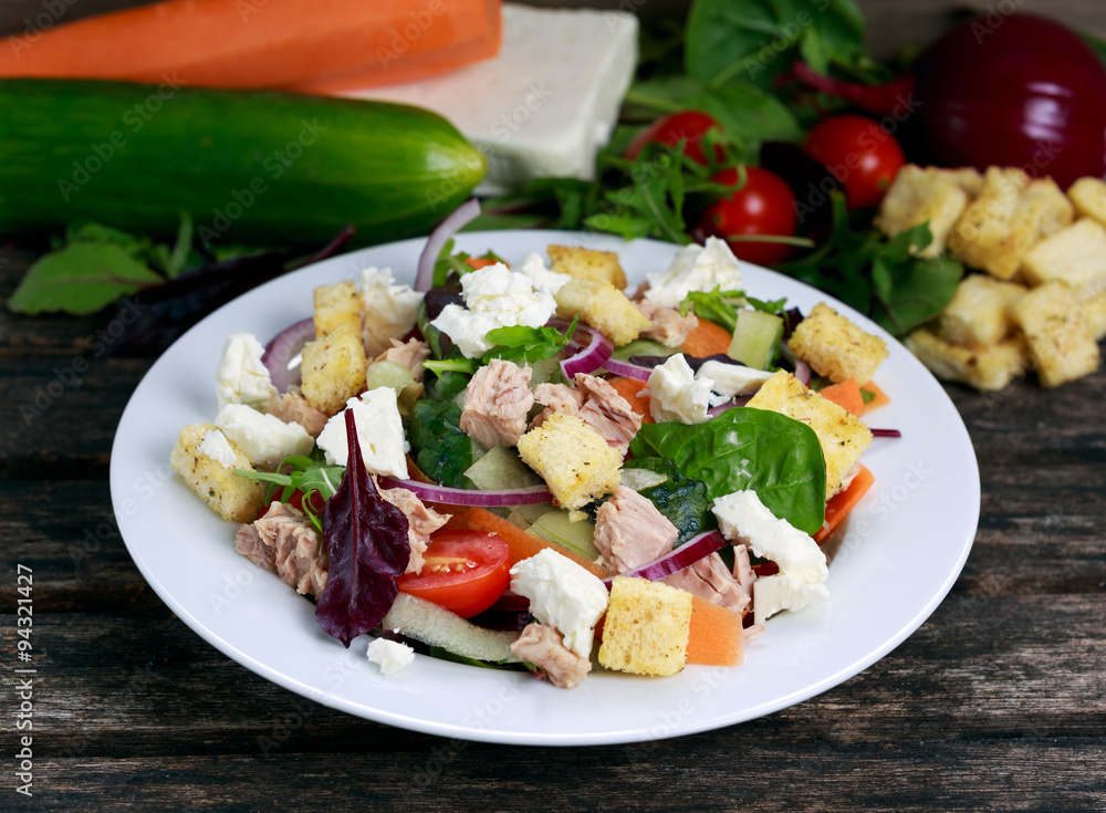 Tuna salad with Spinach, rocket, red ruby chard, tomatoes, cucumbers, white cheese, carrot, red onion, croutons, on old wooden table background Tuna salad with Spinach, rocket, red ruby chard, tomatoes, cucumbers, white cheese, carrot, red onion, croutons, on old wooden table background