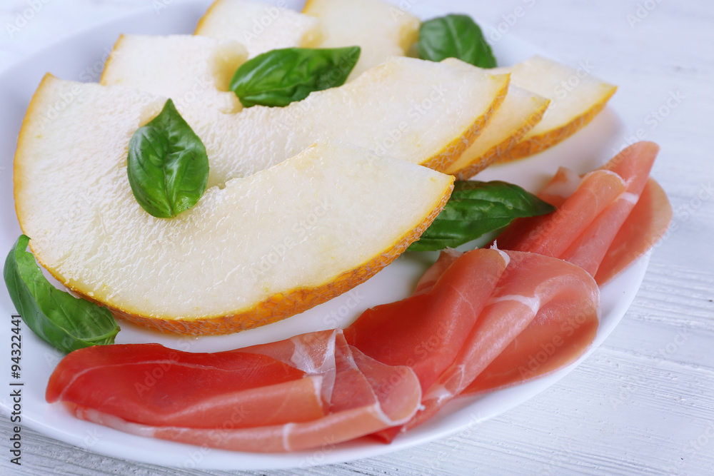 Melon with prosciutto of Parma ham on wooden table, closeup